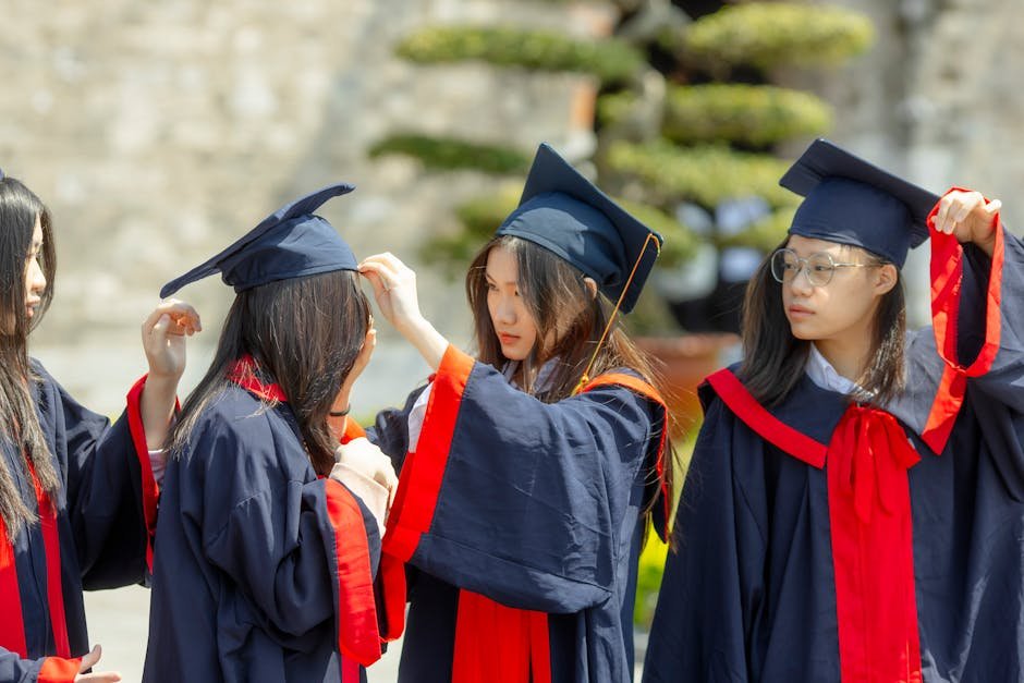 Group of young Asian women celebrating graduation outdoors in academic gowns.