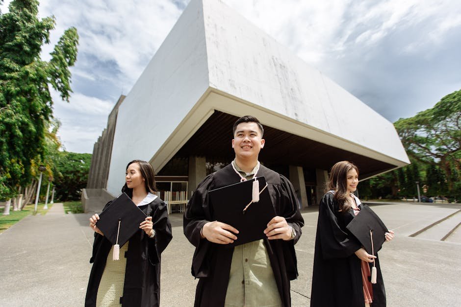 Three graduates celebrating outside a contemporary building with diplomas in hand.