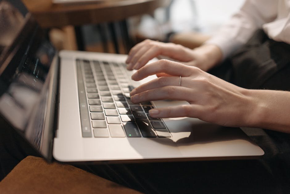 Close-up of hands typing on laptop in a cozy setting, ideal for remote work content.